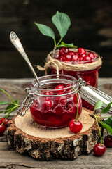 Fresh red cherries fruit on wooden background. Jar of cherry jam and sour cherries. Berries cherry with syrup. Canned fruit. vertical image. top view. place for text