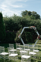 white wedding arch decorated with flowers at the wedding ceremony in summer