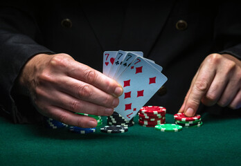A player bets on a winning combination of four of a kind or quads in a game of poker on a green table with chips in a club - obrazy, fototapety, plakaty