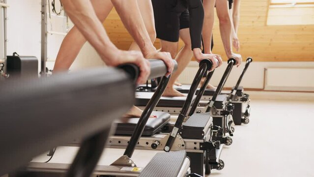 Group of women exercising on reformer in gym. Training instructors for working with clients. Woman training pilates on the reformer. Pilates exercises lying on pilates workout.