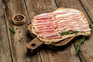 Close up Bacon slices. Pig meat. Pork belly with rosemary on a wooden board, Keto diet food ingredients. Restaurant menu, dieting, cookbook recipe
