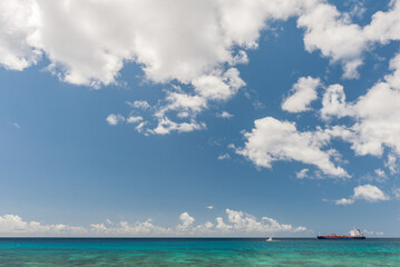 Obraz premium Coastline in Barbados with Caribbean ocean, Clear Blue Sky and Giant Ship in Background.