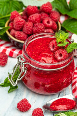 Homemade raspberry jam in jar with raspberries and mint. vertical image. top view. place for text