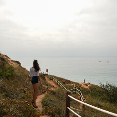 Girl treading down a trail overlooking the sea