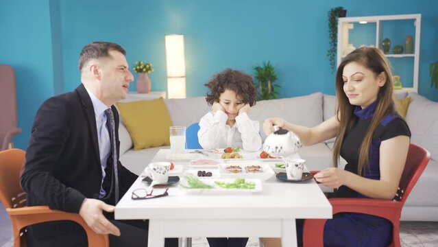 Parents who have breakfast in the morning make their unhappy children laugh and entertain.
The grumpy boy at the breakfast table is noticed by his parents, and the parents make him laugh and cheer up.
