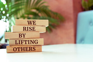 Wooden blocks with words 'We Rise by Lifting Others'.