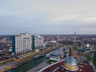 Obraz premium Sunset in Bremerhaven with houses and ships and the (bremer Schiffahrts-Museum), Klimahaus and the coast line of Bremerhaven (technik museum) taken from 90 m high bulding, Monochrom, sepia, panorama