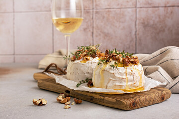 Brie or camembert cheese with thyme, nuts, honey, grissini and glass of white wine
