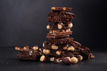 Pieces of chocolate bars with nuts on dark background