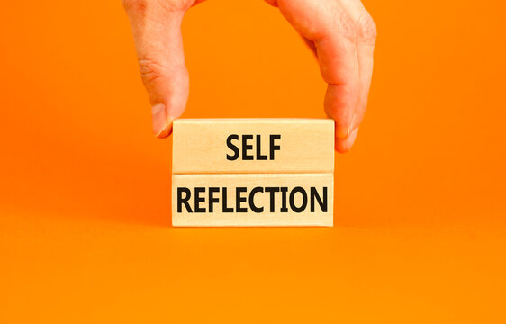 Self reflection symbol. Concept word Self reflection typed on wooden blocks. Beautiful orange table orange background. Businessman hand. Business psychological and self reflection concept. Copy space.