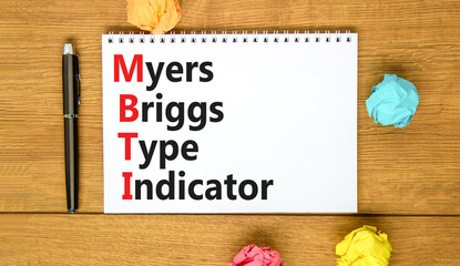 MBTI Myers Briggs type indicator symbol. Concept words MBTI Myers Briggs type indicator on white note on beautiful wooden background. Psychological MBTI Myers Briggs type indicator concept. Copy space