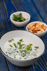 yogurt soup with herbs and crackers on a blue wooden table