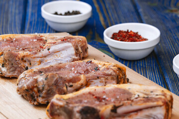 Raw pork meat and ingredients on a board on blue desk