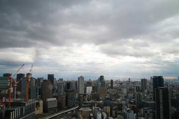 Obraz premium Overhead view of Osaka's Umeda area from a hill on a cloudy day, sunlight shining through a gap in the clouds.