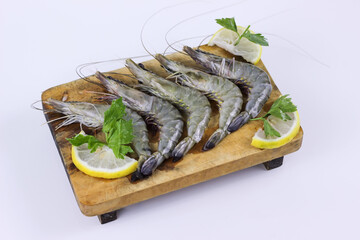 Fresh raw shrimps on wooden cutting board plate with lemon