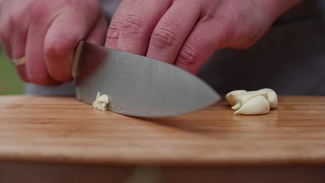 footage of cook cuts garlic close-up