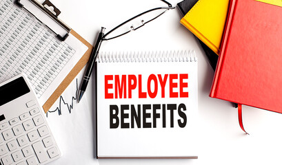 EMPLOYEE BENEFITS text on notebook with clipboard and calculator on white background