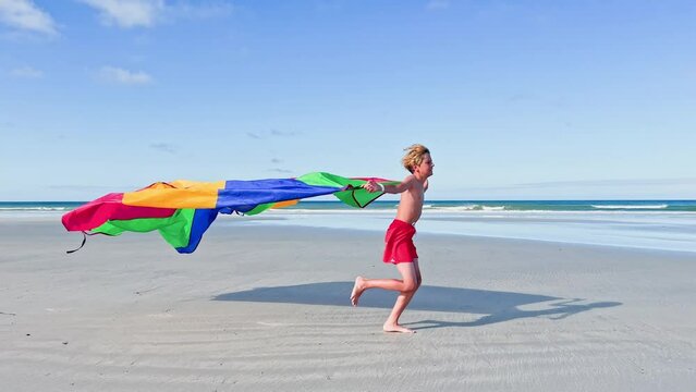 Boy run with a color parachute fabric fly on wind
