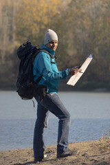 Portrait of traveler man at lake in autumn with a map
