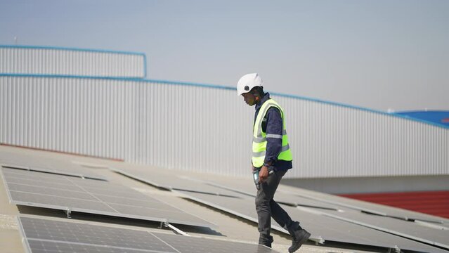 Engineer on rooftop sitting next to solar panels photo voltaic check alignment for good installation
