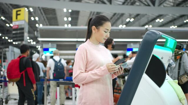 People travel on holiday vacation and global airplane transportation concept. Attractive Asian woman holding passport and using self check-in kiosks machine getting boarding pass in airport terminal.