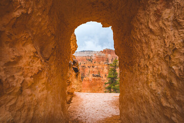 hiking trail through sandstone tunnel at bryce canyon