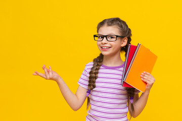 A teenage girl with colorful notebooks in her hands and glasses. A little girl is getting ready for school. Additional courses for the child.