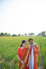 Indian farmer couple holding onion crop and giving happy expression at field.
