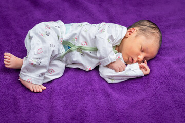 newborn baby isolated sleeping in white cloth with purple background from different angle
