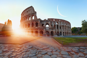 Fototapeta premium Colosseum in Rome with crescent moon at amazing sunrise - Colosseum is the best famous known architecture and landmark in Rome, Italy