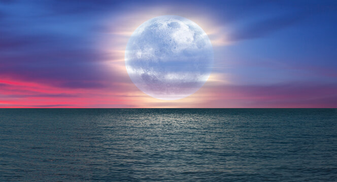 Night sky with moon in the dark clouds and darkblue sea in the foreground "Elements of this image furnished by NASA"
