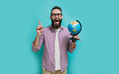 Smiling hipster man holding a globe in his hands. The concept of travel, vacation, see the world.