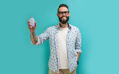 Young bearded charismatic hipster advertises a bright wireless computer mouse. Product presentation