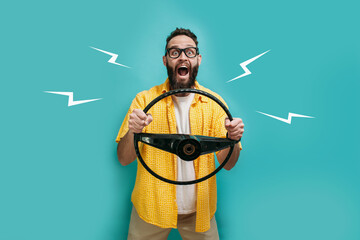 Portrait of a funny emotional hipster guy dressed in casual clothes with a steering wheel in his...