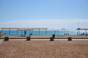 Summer. Beach. Beach umbrellas on an empty sandy beach. End of season. Issyk-Kul. Kyrgyzstan.