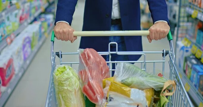 single man shopping in food store, closeup of hands on cart with vegetables, top view, 4K, Prores