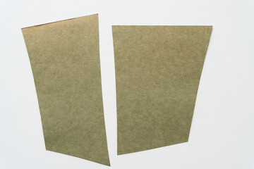 two faded and or discolored moss green paper shapes on blank paper