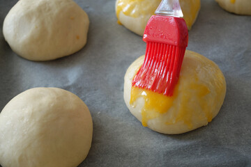 Brushing egg on raw cake dough, applying egg yolk on raw dough,