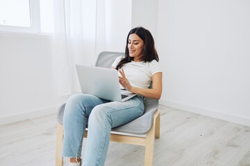 Woman relaxing at home sitting in a chair with a laptop, lifestyle home mood. Mockup, free copy space