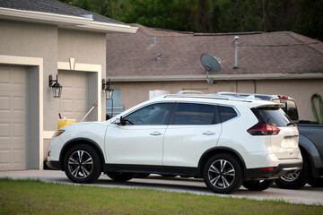 Car parked in front of wide garage double door on concrete driveway of new modern american house