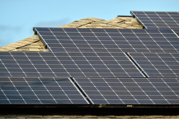 Fototapeta premium Private home roof covered with solar photovoltaic panels for generating of clean ecological electric energy in suburban rural town area. Concept of autonomous house