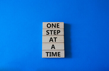 One step at a time symbol. Concept words One step at a time on wooden blocks. Beautiful blue background. Business and One step at a time concept. Copy space.