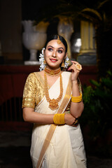 Magnificent young Indian bride in luxurious bridal costume with makeup and heavy jewellery standing...