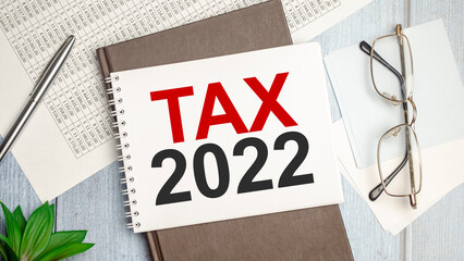 Tax 2022, taxation system. Word white notebook and papers