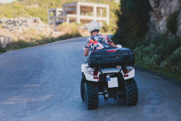 Fototapeta na wymiar Group of riders riding ATV vehicle crossing mountain serpentine road track, process of driving rental vehicle, all terrain quad bike vehicle, during off-road tour, Greece, Ionian sea islands
