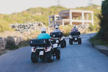 Group of riders riding ATV vehicle crossing mountain serpentine road track, process of driving rental vehicle, all terrain quad bike vehicle, during off-road tour, Greece, Ionian sea islands