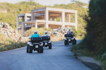 Group of riders riding ATV vehicle crossing mountain serpentine road track, process of driving...