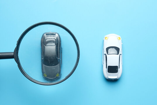 Selective focus picture of magnifying glass selecting black car with car insigt. Choose your best car to drive.