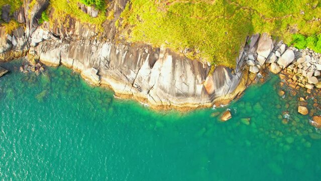 Top aerial view over "Krating cape" during sunlight, Rocky shoreline and the yellow meadow that covers the mountains. Stunning beautiful sunset view point in Phuket, Thailand, Southeast Asia. 4K
