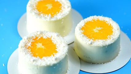 Small cakes with orange and coconut on a blue background.